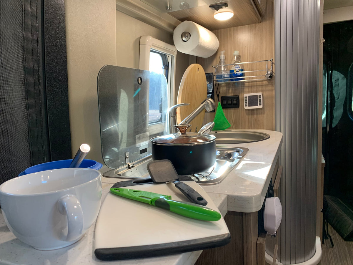 and distant mountains under blue sky.|Dark gray RV rental parked at a serene woodland campsite with bare trees and a smoky campfire.|Scenic mountain overlook with a grey RV rental parked — photo 13