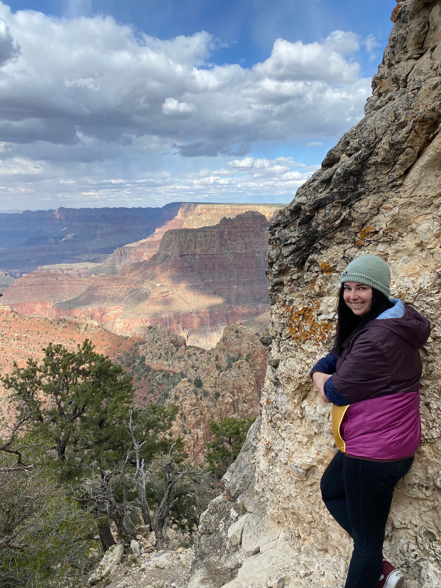 Smiling woman by Grand Canyon cliff. See vast, sunlit canyon layers. Plan your next RV rental adventure!