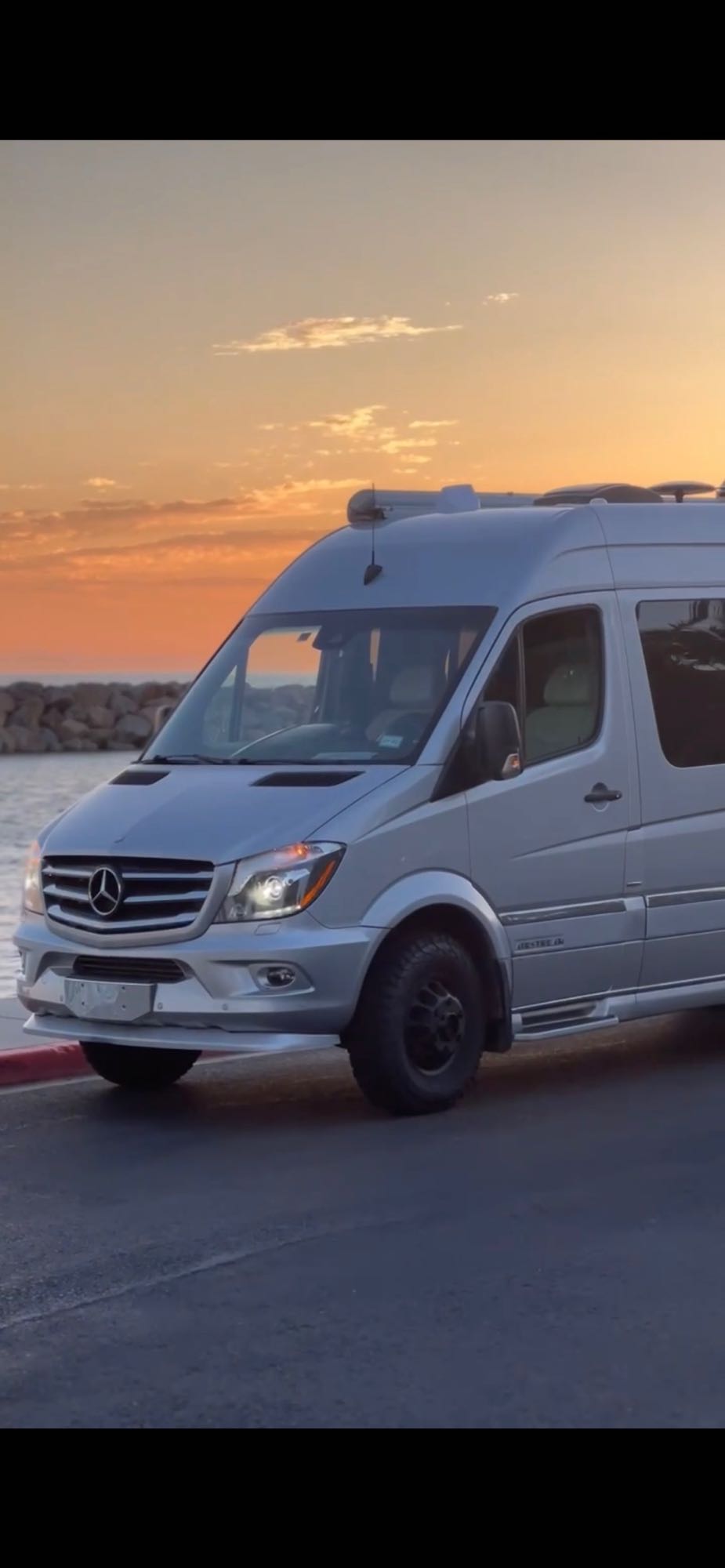 Silver Mercedes Sprinter RV rental, adventure-ready and parked seaside at sunset. — photo 2