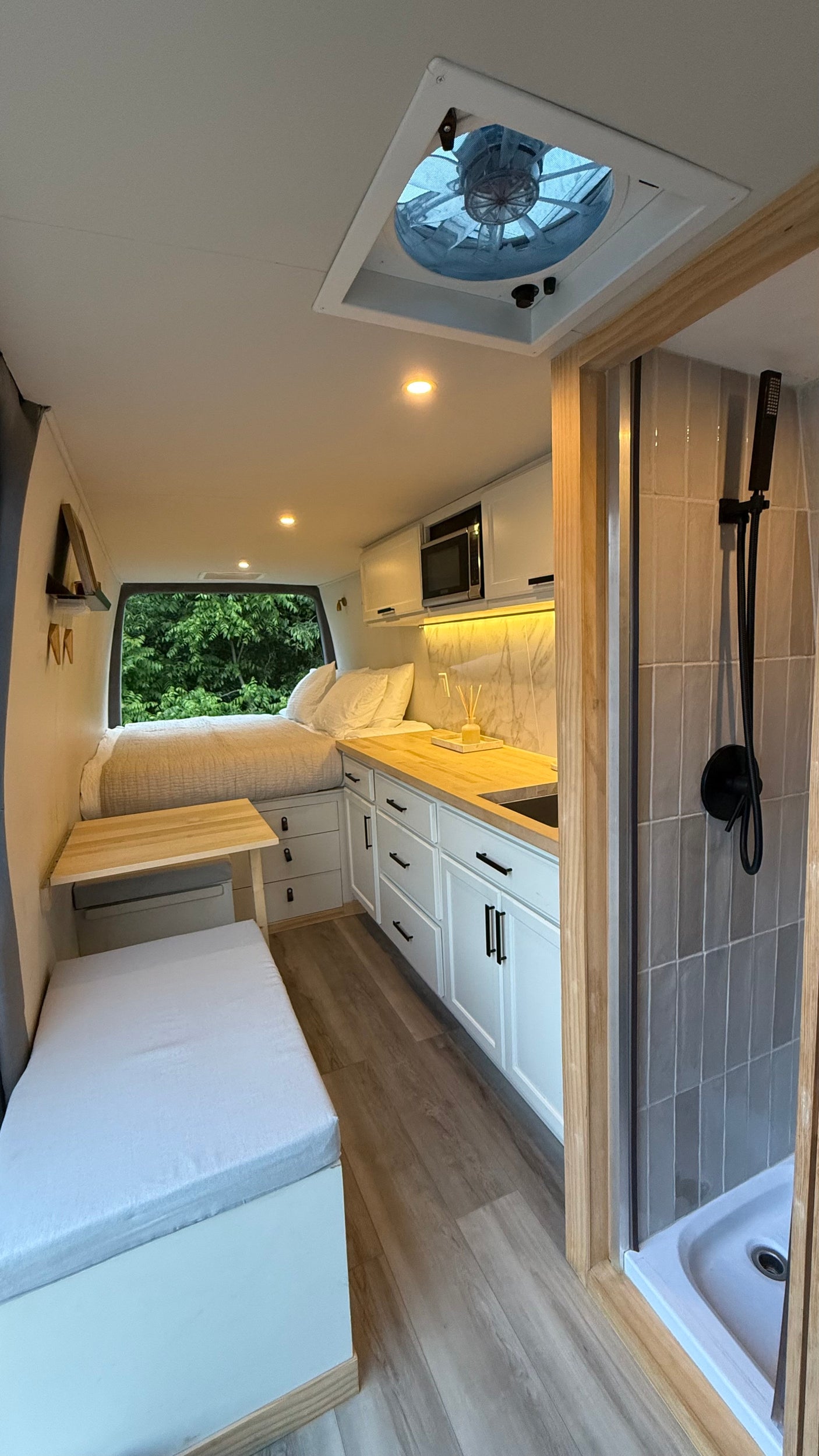 Spacious RV rental van conversion featuring a cozy bedroom, full kitchenette, and private shower for comfortable mobile living.