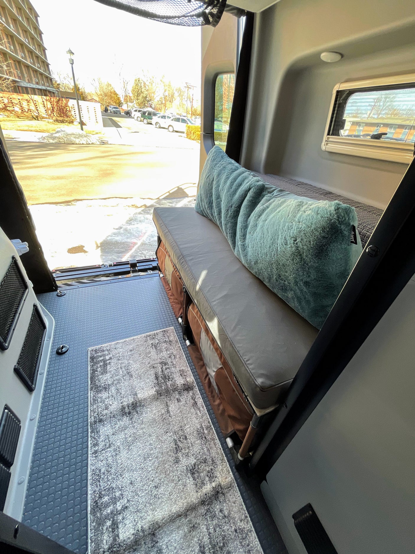 This RV rental features comfortable bench seating with storage below, a floor rug, and an outdoor view.