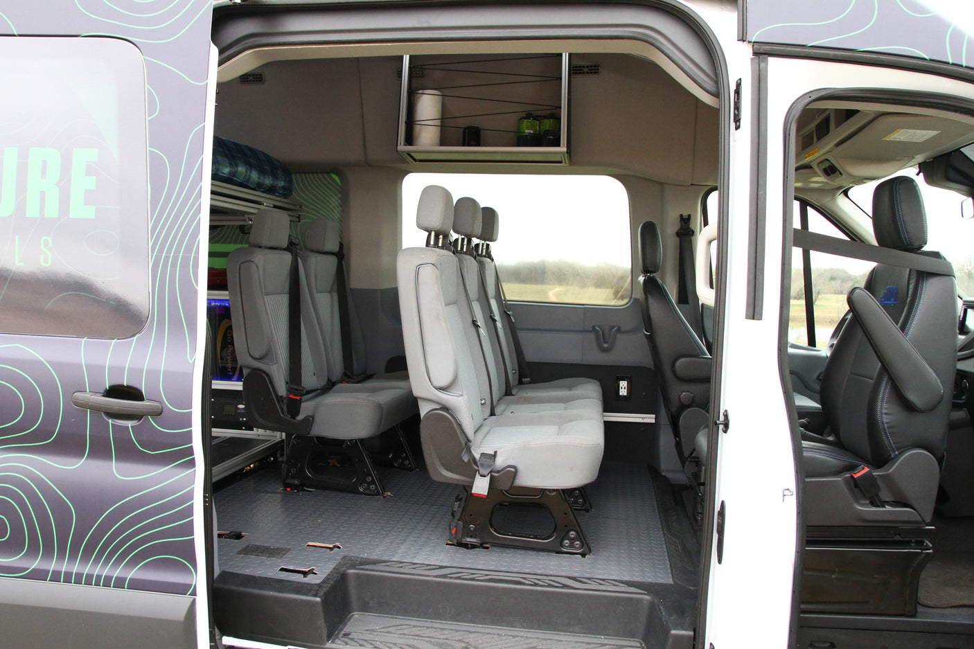Spacious RV rental interior with multiple passenger seats, overhead storage, and durable flooring for comfortable group travel.