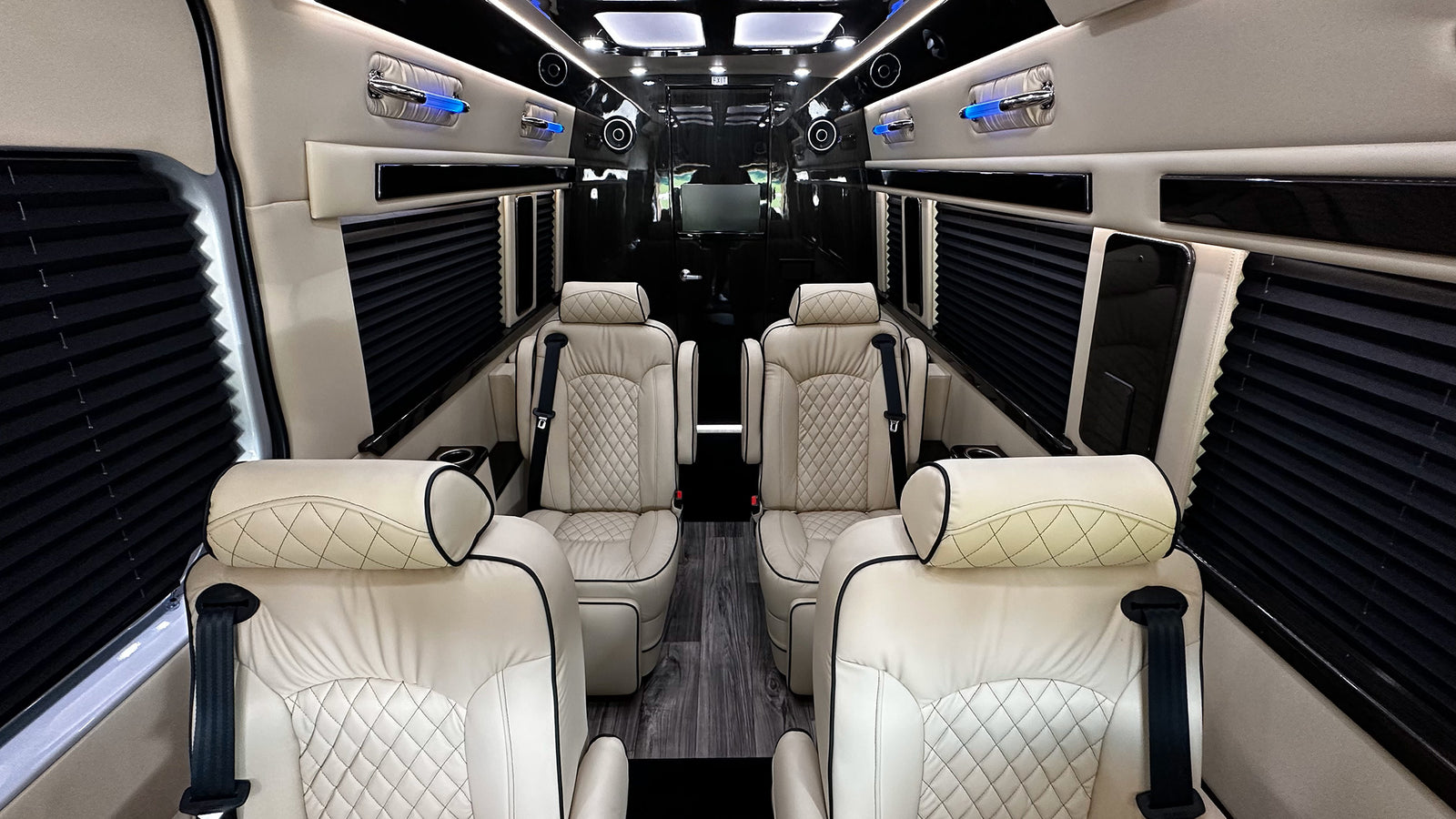 Luxury RV rental interior with cream leather seats, black accents, privacy blinds, and blue ambient lighting.