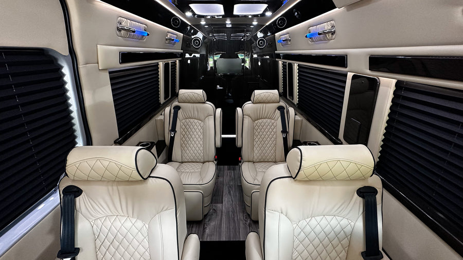 Luxury RV rental interior with cream leather seats, black accents, privacy blinds, and blue ambient lighting.