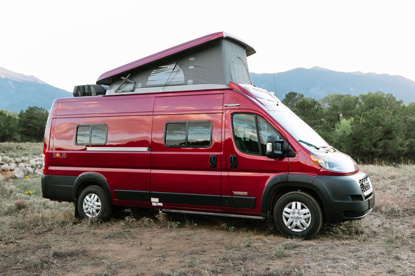 Red Winnebago Solis pop-top RV rental parked in a scenic mountain landscape