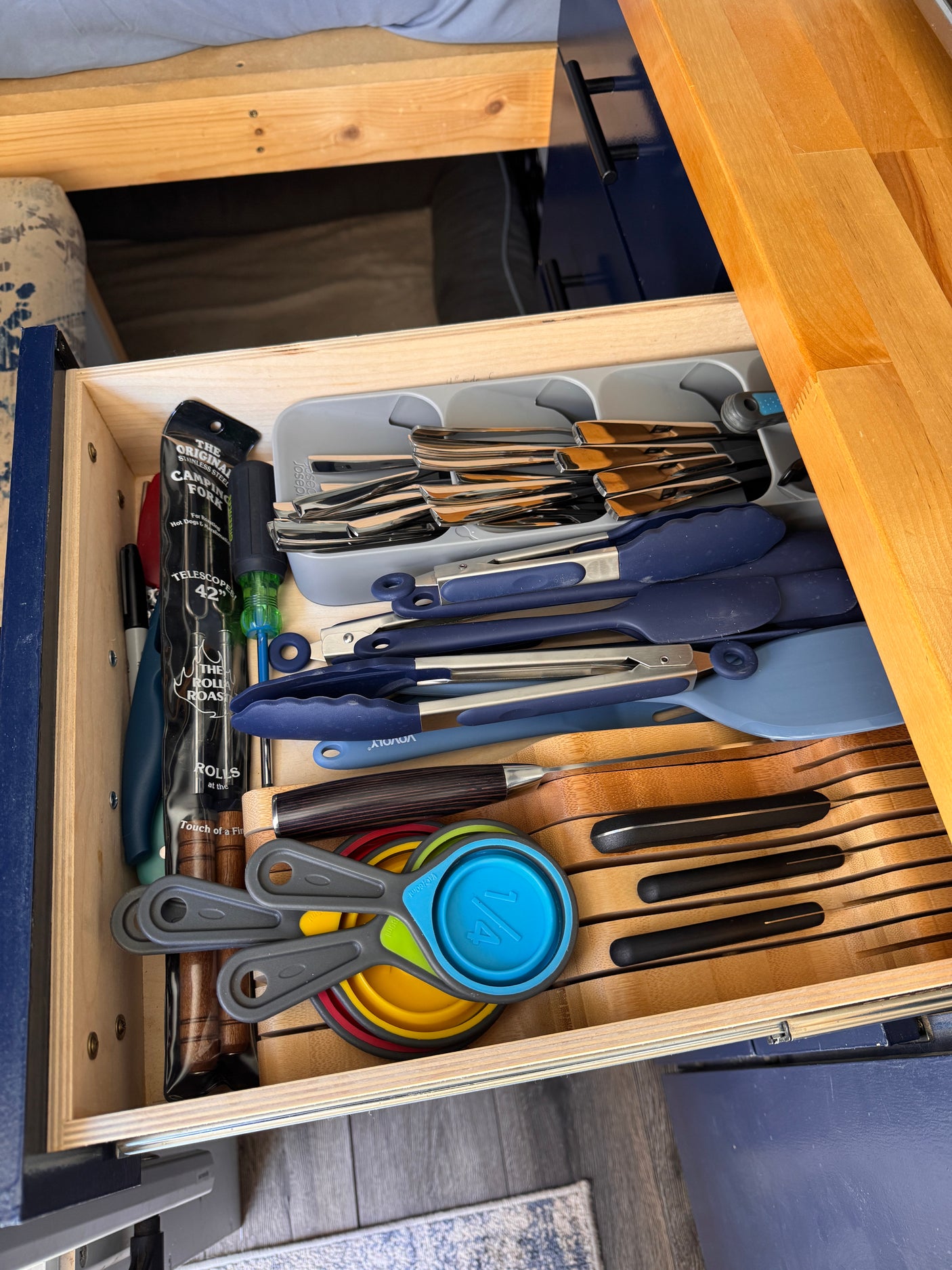 A well-organized kitchen drawer in an RV rental, stocked with silverware, cooking tools, and even a camping fork.