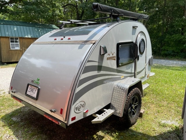 A modern, silver nuCamp T@G Boondock teardrop trailer, equipped with off-road tires, an excellent choice for RV rental camping.
