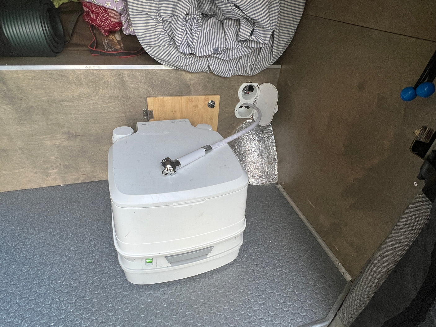 RV rental: Compact interior showing a portable toilet with sprayer, offering essential sanitation for travel.