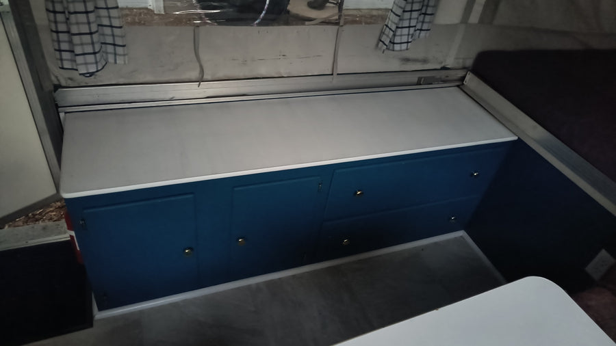 RV rental: Renovated interior with vibrant blue cabinets, white countertop, and cozy sleeping area.