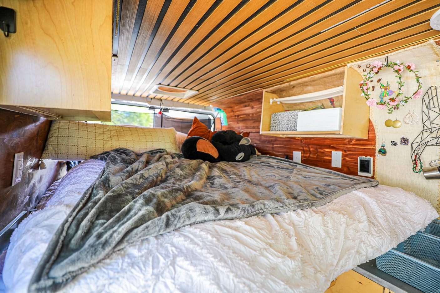 Cozy RV rental bedroom with custom wood interior, comfortable bed, and unique decor for a homey feel.