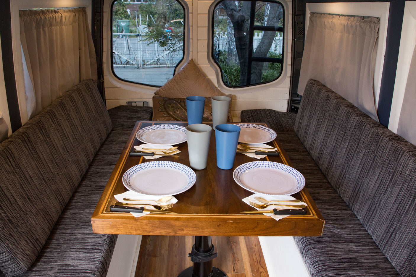 RV rental interior: A cozy dining area with a wooden table set for four, flanked by cushioned benches and windows.