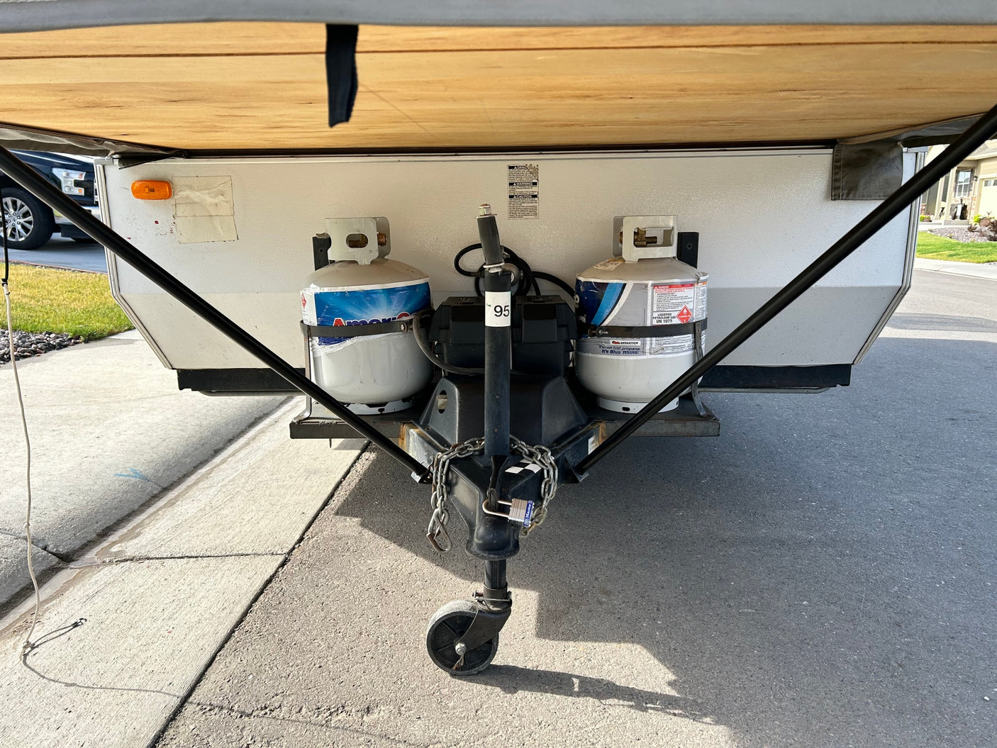 Front view of an RV rental showing its hitch, dual propane tanks, and jack stand, ready for towing.