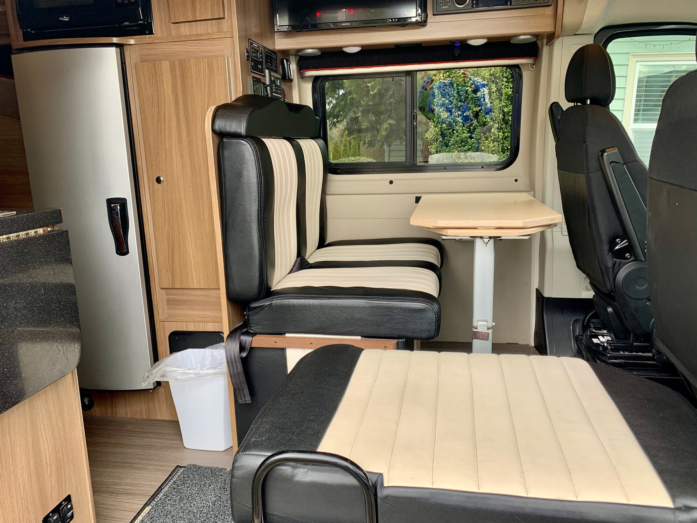 RV rental: Dinette with black & beige striped seating, table, fridge, microwave, & window view.