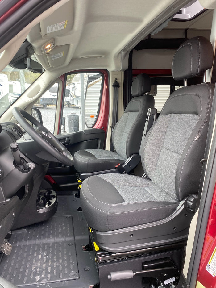 RV rental: Bright, clean van interior featuring front driver and passenger seats, steering wheel, and durable floor mat.