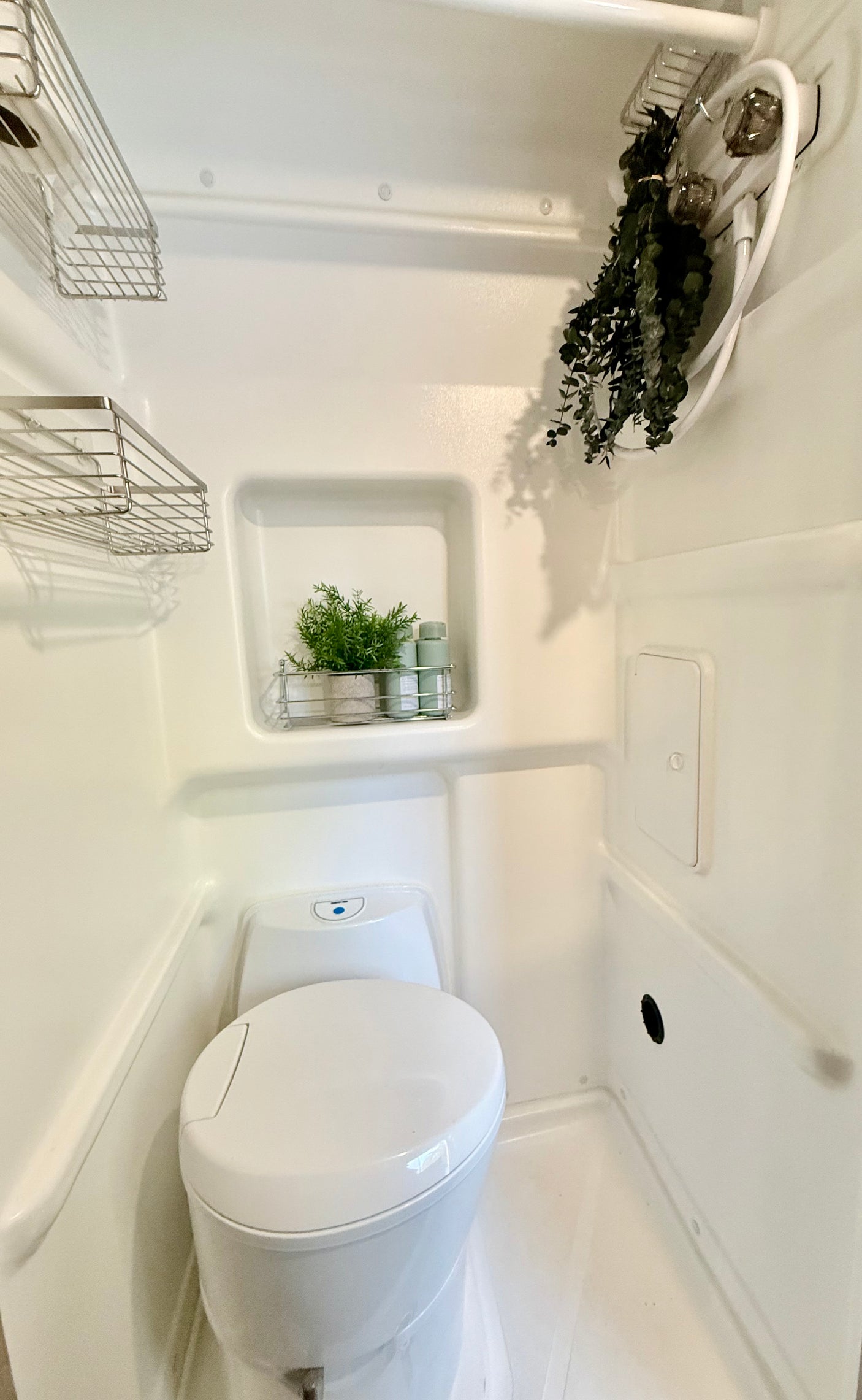 Explore this modern RV rental wet bath, complete with a toilet, shower, and practical storage solutions.