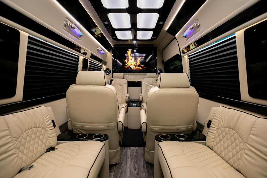 Luxury RV rental: plush cream quilted leather seating, ambient lighting, large entertainment screen, and wood floor.