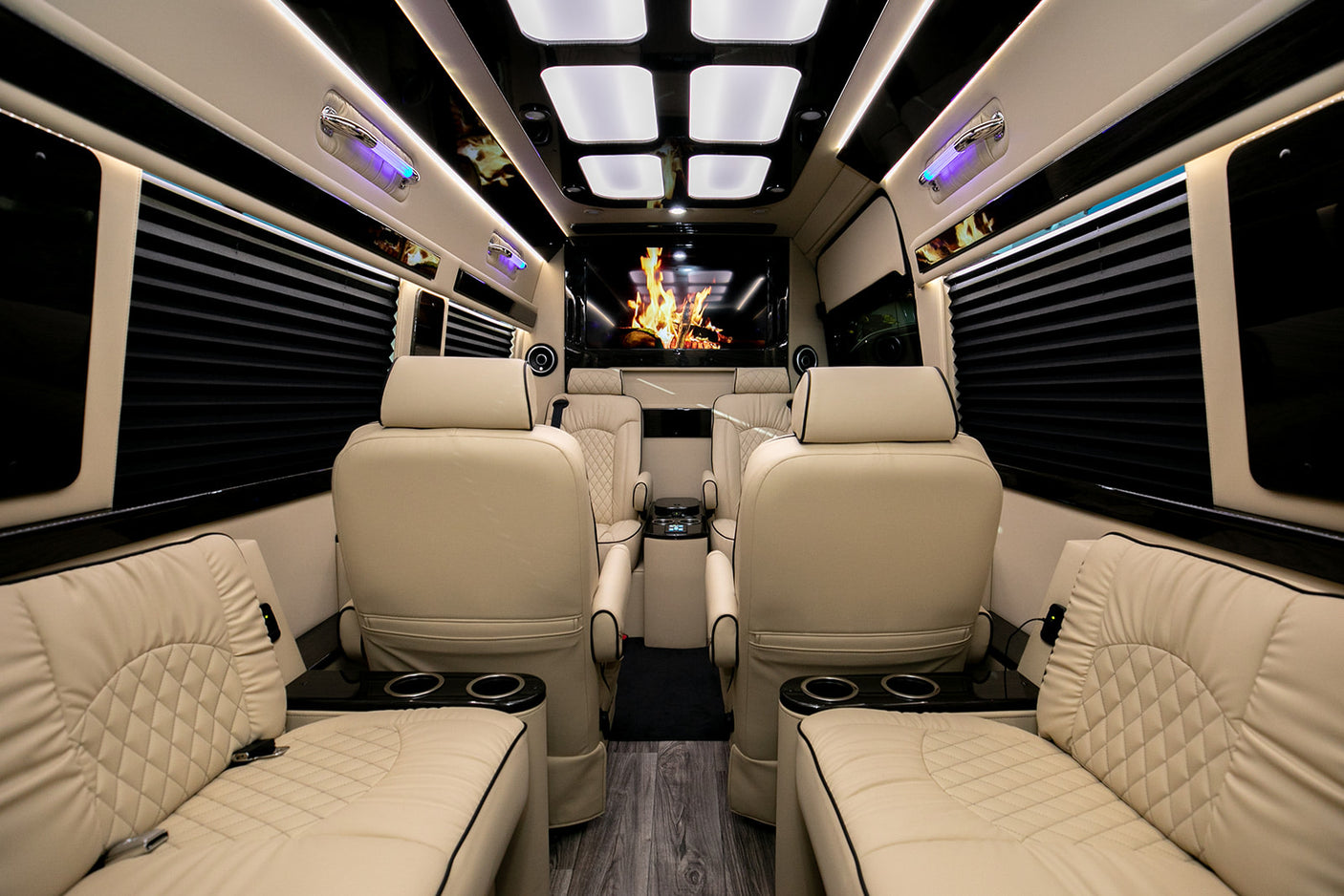 Luxury RV rental: plush cream quilted leather seating, ambient lighting, large entertainment screen, and wood floor.