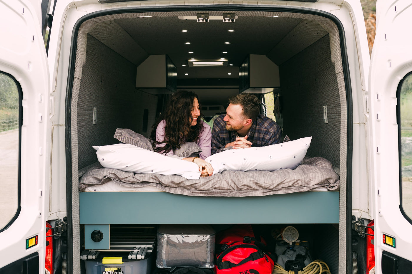 Cozy RV rental van interior with a smiling couple on the bed, enjoying their van life adventure. — photo 20