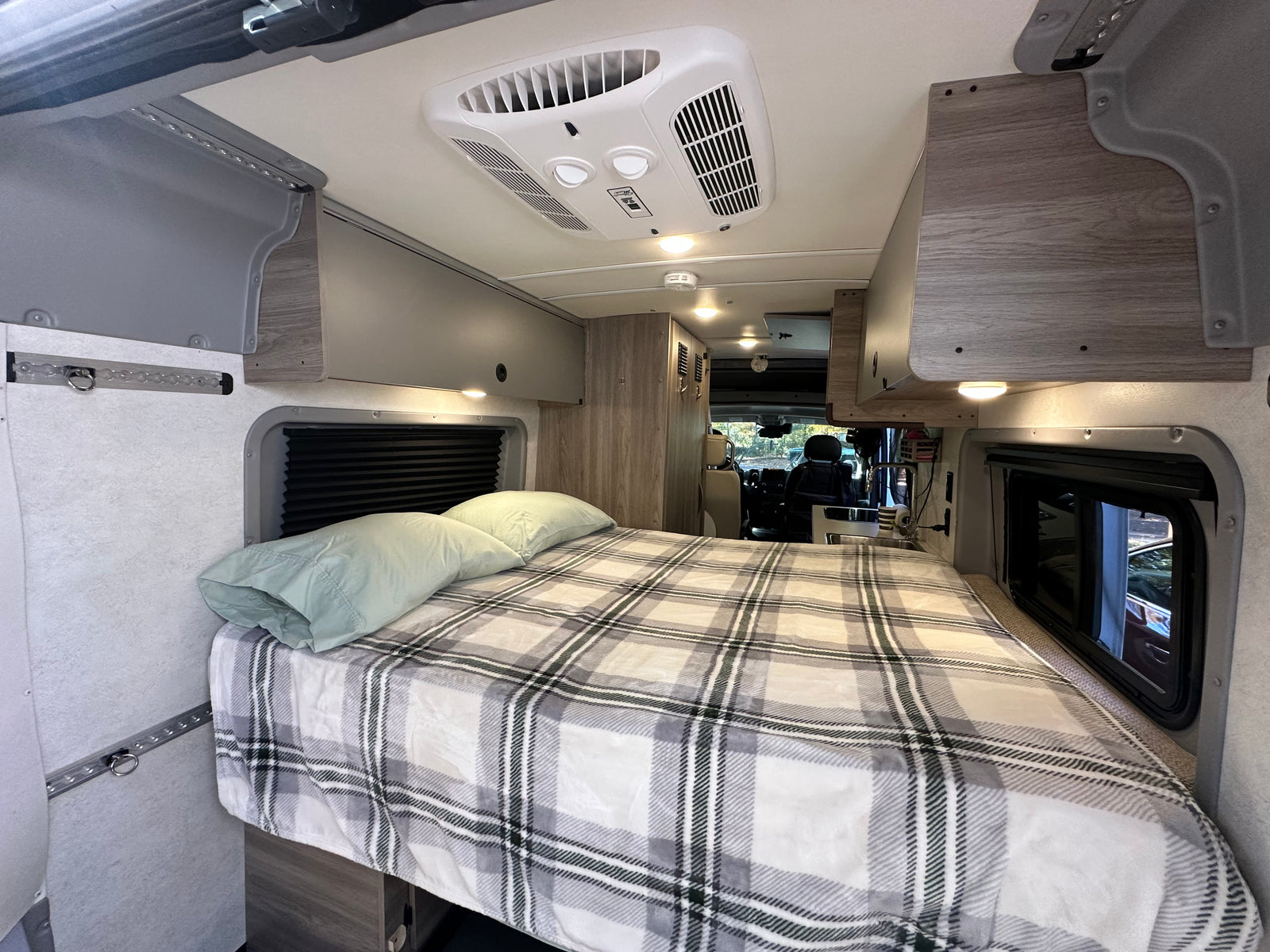 and plush bench seating. Green views outside.|This rv rental features a compact kitchen with a stove and sink