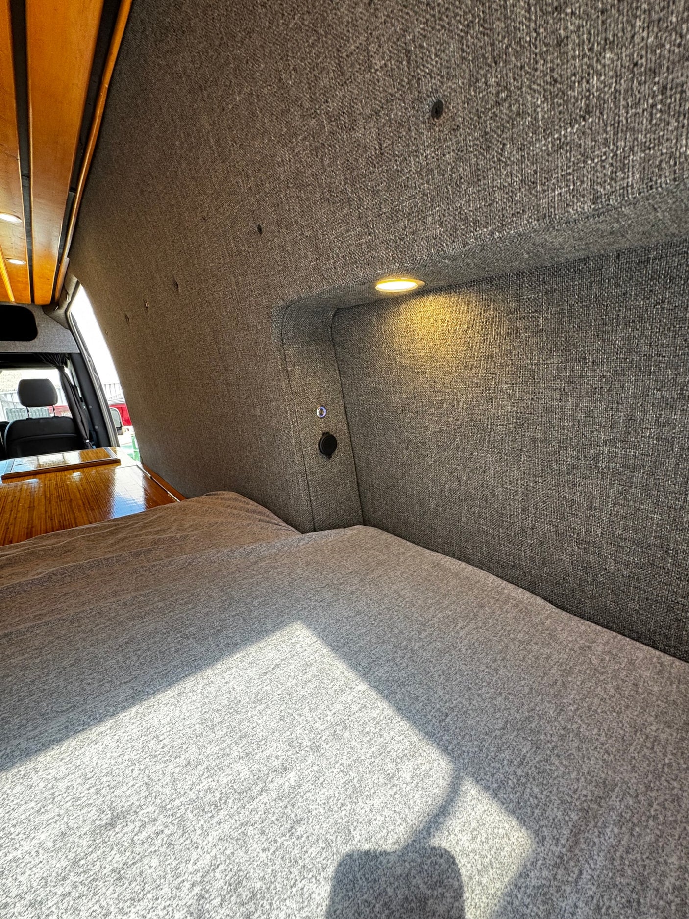 Experience comfort in this RV rental's cozy sleeping area, featuring soft bedding, integrated light, and power outlets.