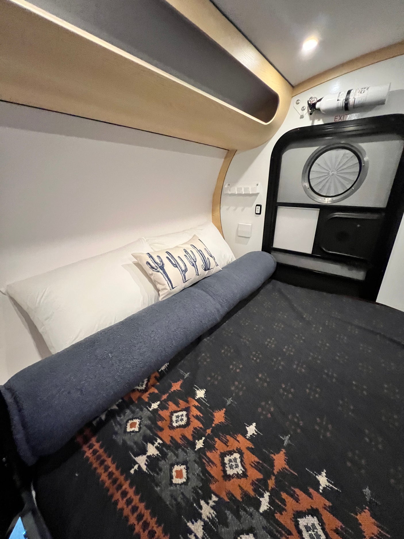 Step inside this cozy RV rental's sleeping area, featuring a Southwestern blanket, cactus pillow, and compact design.