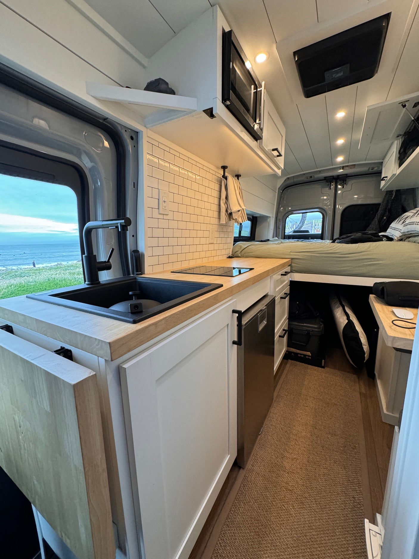 This RV rental boasts a modern kitchen, comfy bed, & ocean views. Compact, bright interior perfect for van life adventures.