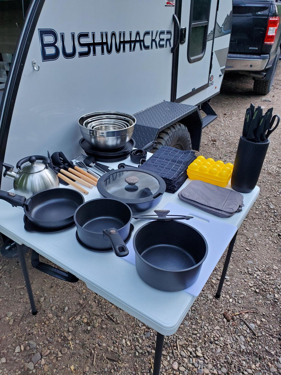 surrounded by green trees for camping.|A Bushwhacker teardrop rv rental with an open outdoor kitchen