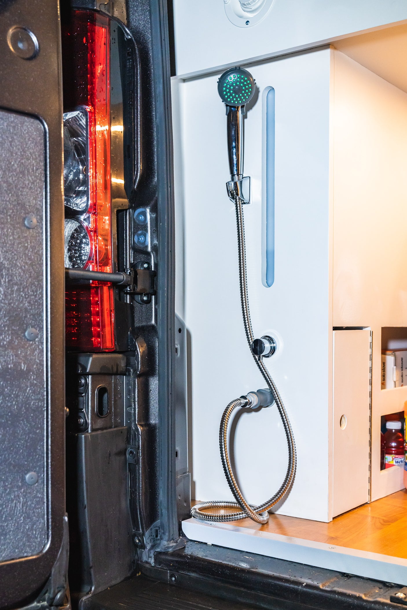 RV rental: Tailgate view revealing a convenient outdoor shower system built into the van's custom interior.