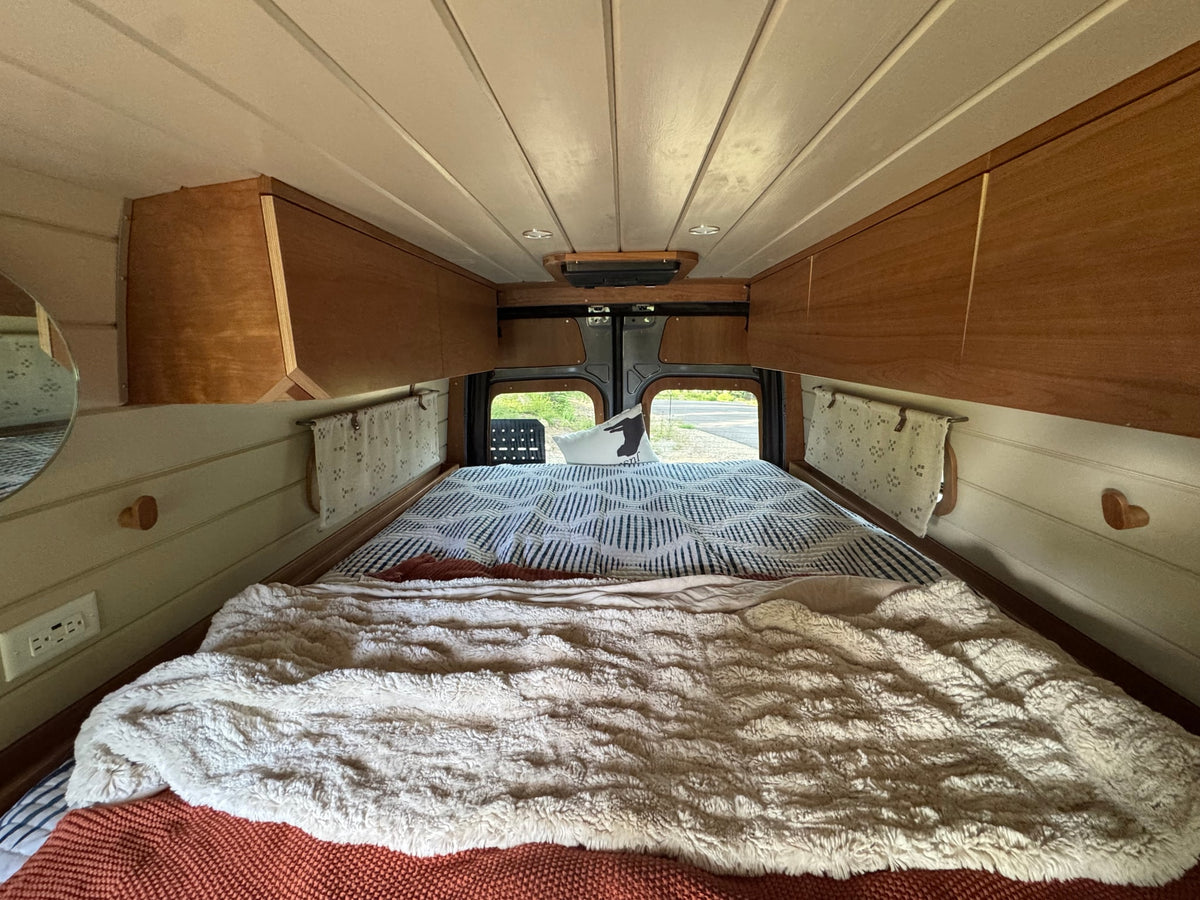 surrounded by tall pine trees under a cloudy sky.|Grey custom Sprinter van with a roof rack — photo 7