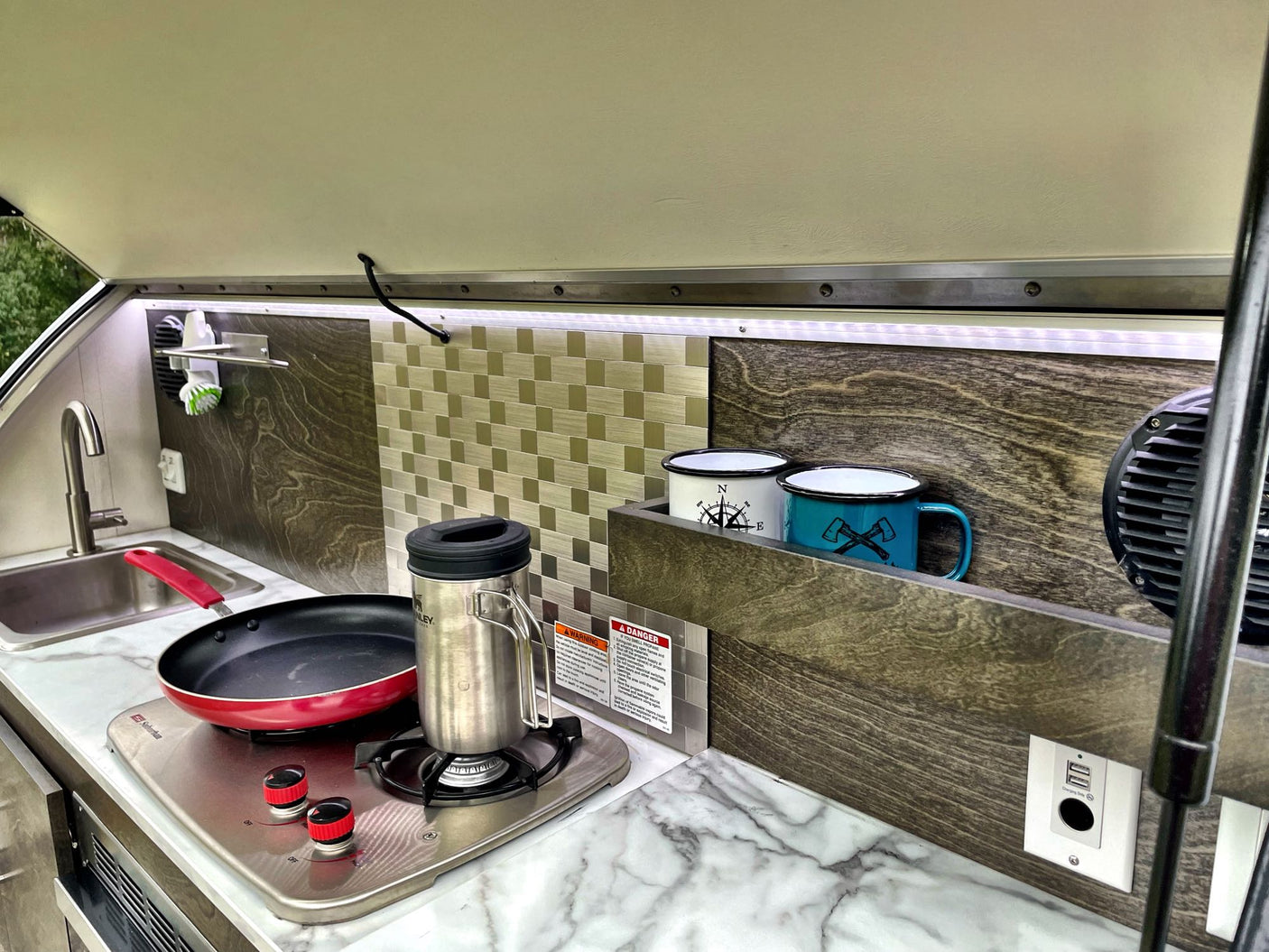 overlooking green nature.|RV rental: A window with an integrated mesh screen and pleated privacy blind. Digital clock shows 5:30 AM.|Inside an RV rental: a pleated window blind