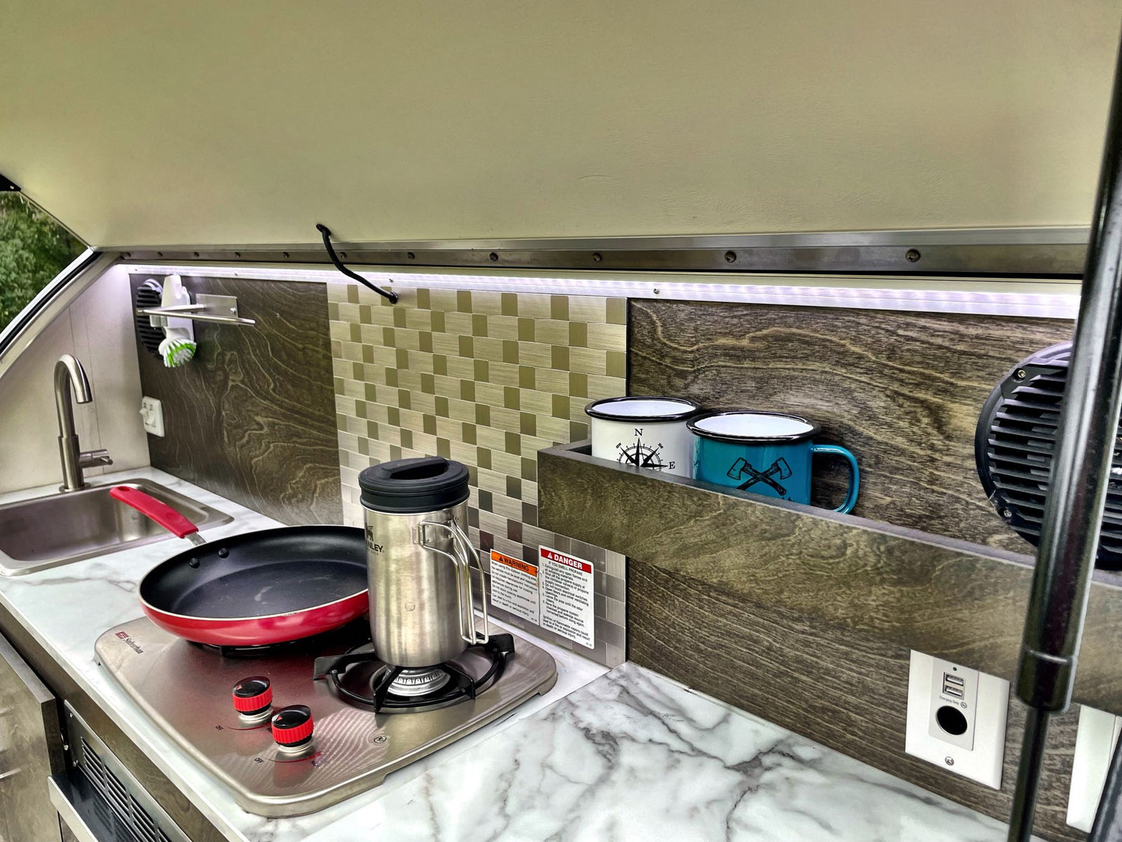 overlooking green nature.|RV rental: A window with an integrated mesh screen and pleated privacy blind. Digital clock shows 5:30 AM.|Inside an RV rental: a pleated window blind