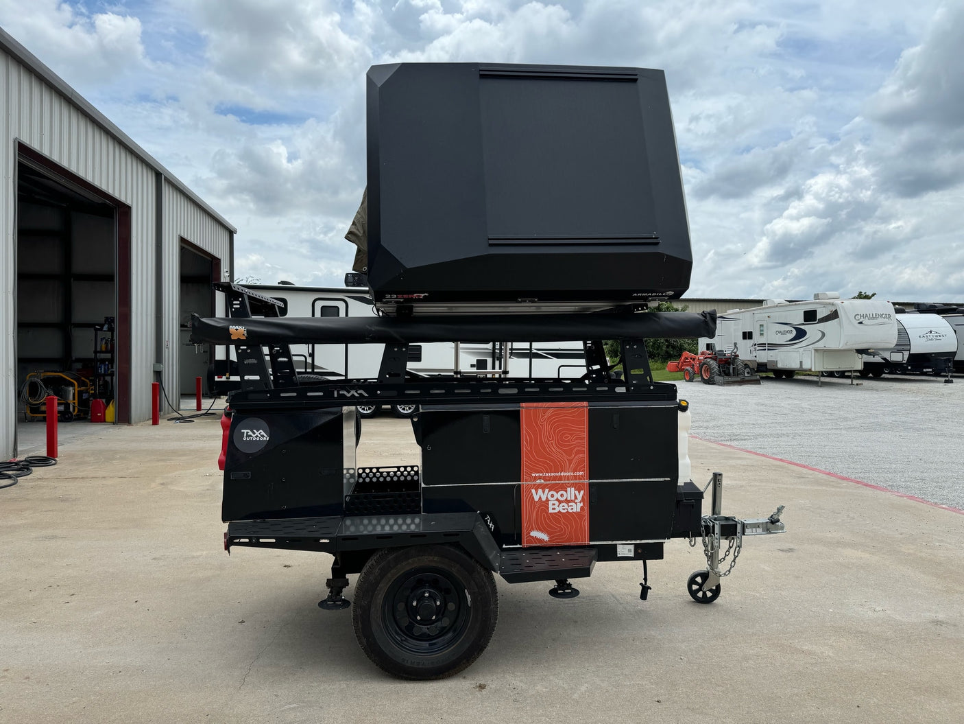 Black Taxa Outdoors Woolly Bear overland trailer with rooftop tent, ready for rv rental adventures.