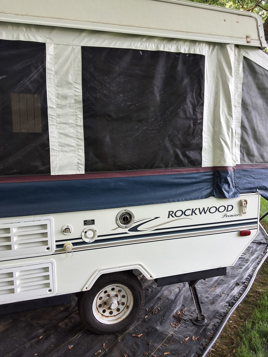 View of a Rockwood Premier pop-up camper (rv rental), showing canvas walls, utility hookups, and wheel.