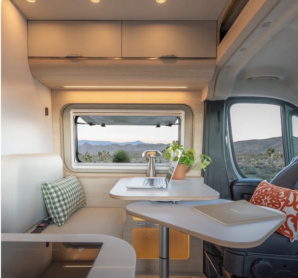 Cozy RV rental interior: a mobile office desk with laptop, plant, and lamp, plus comfy seating & desert views. — photo 5