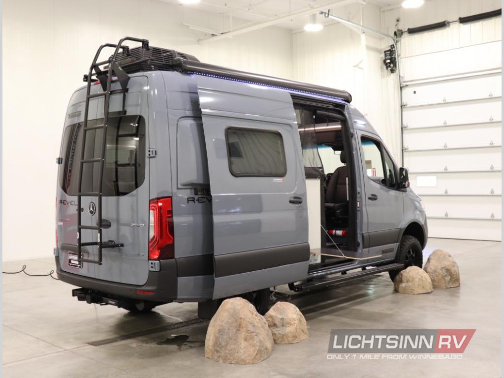 This sleek grey Winnebago Revel camper van, ideal for your next RV rental adventure, features a ladder, roof rack, and open side door.