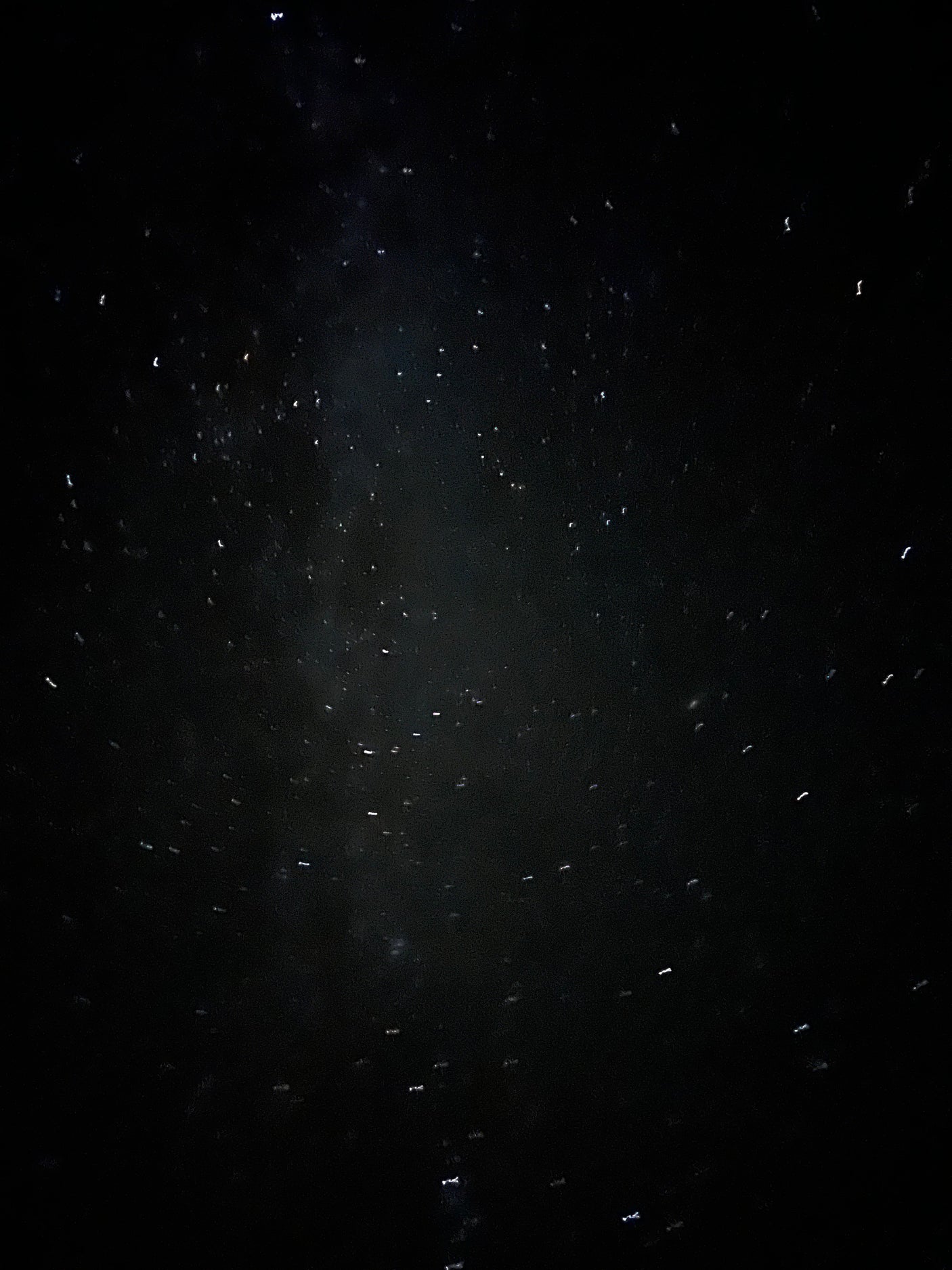 Bright, distorted lights from raindrops on an RV rental window at night.