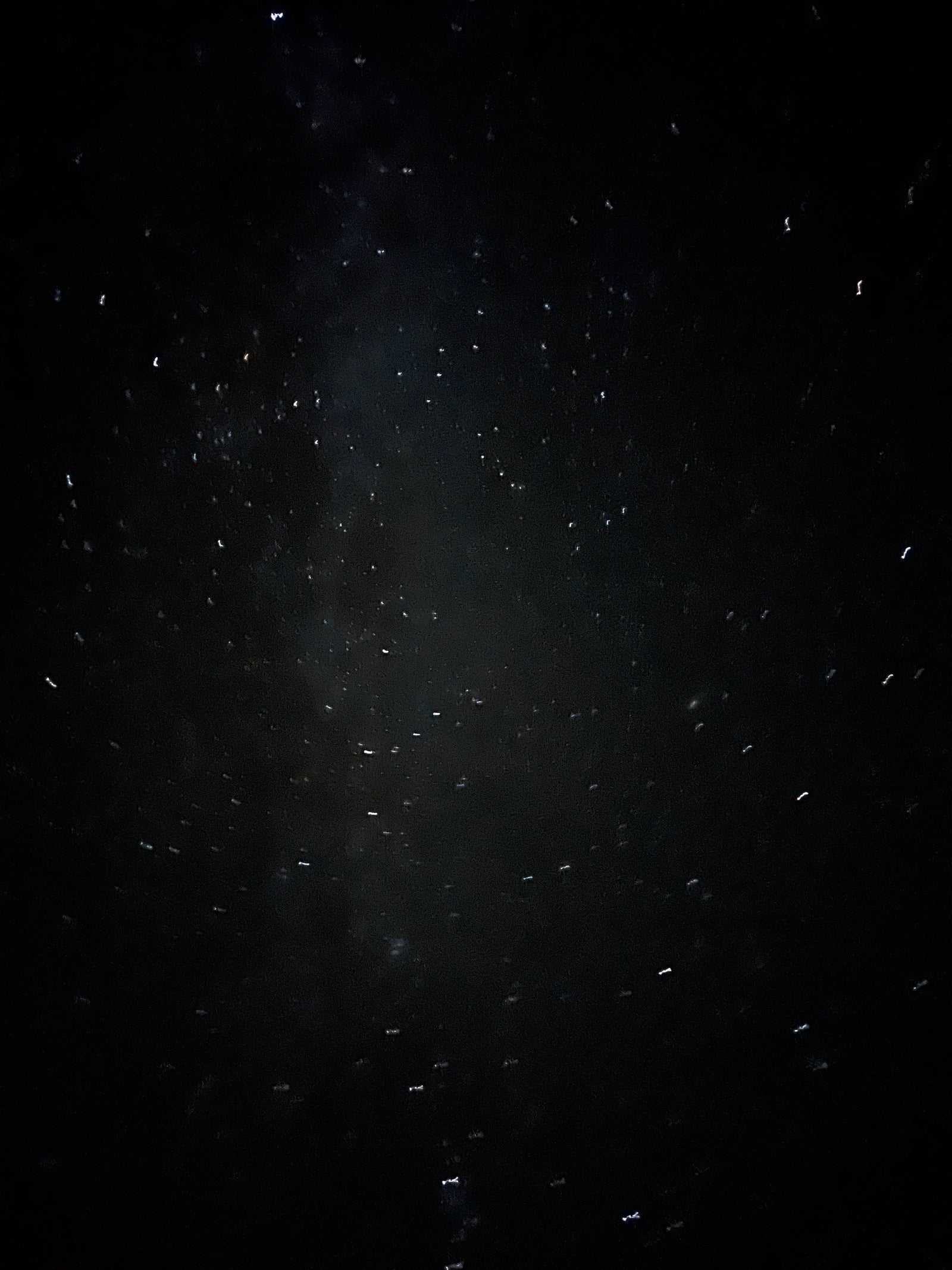 Bright, distorted lights from raindrops on an RV rental window at night.
