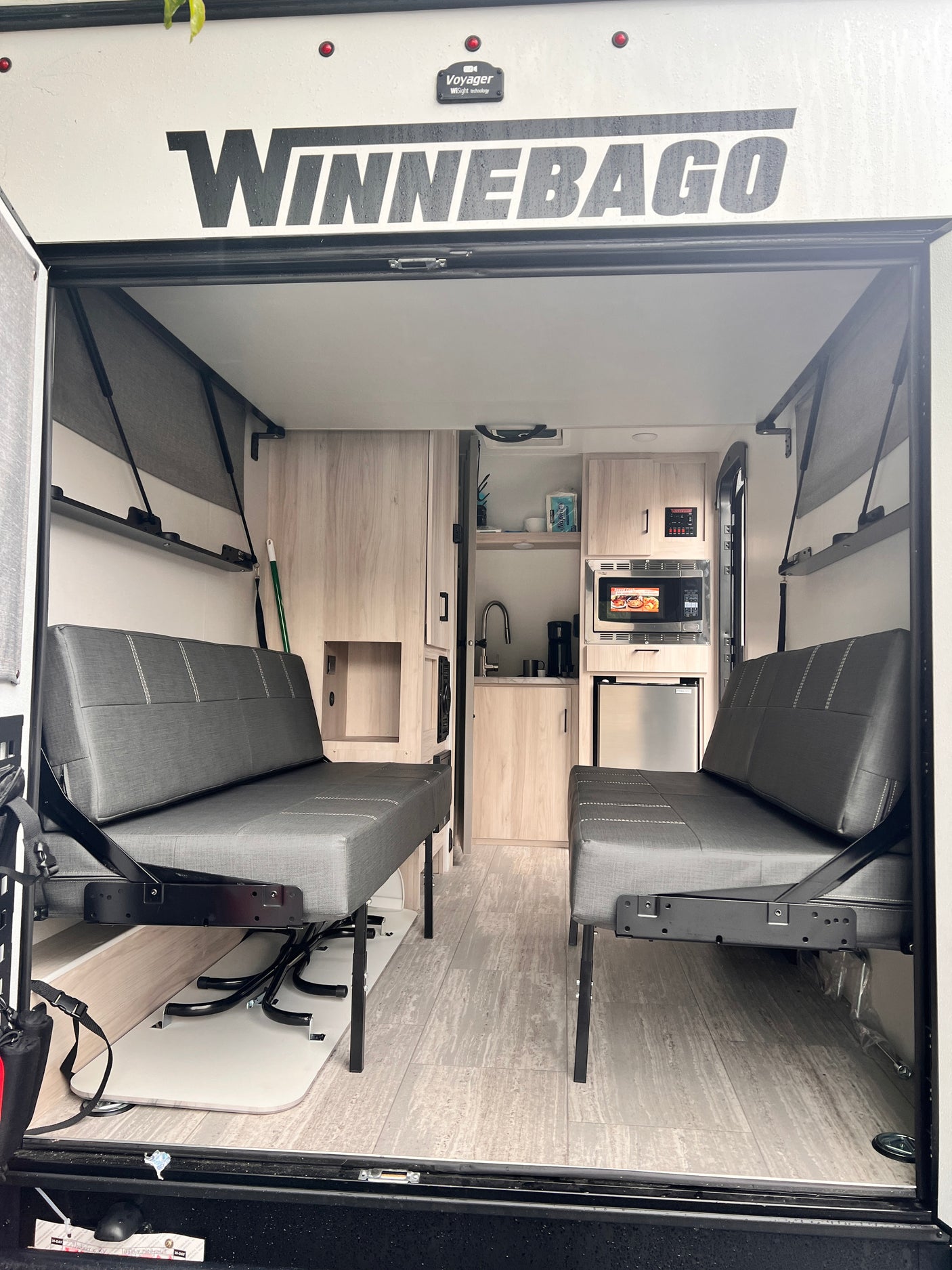 Inside this versatile RV rental: convertible seating, compact kitchen, and ample space, viewed from the open ramp door.