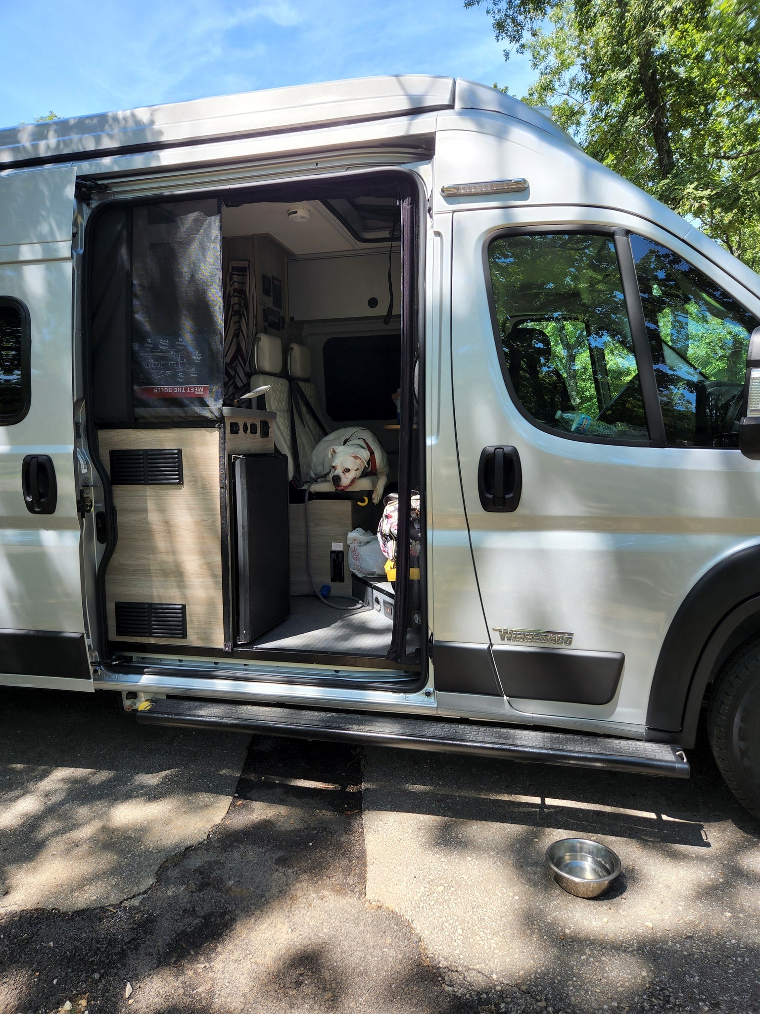 parked on gravel.|Front view of a light Winnebago Ram van