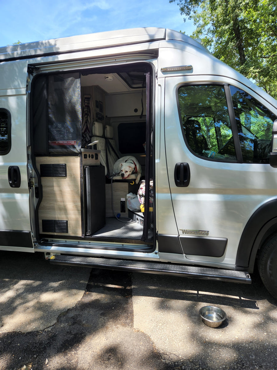 parked on gravel.|Front view of a light Winnebago Ram van