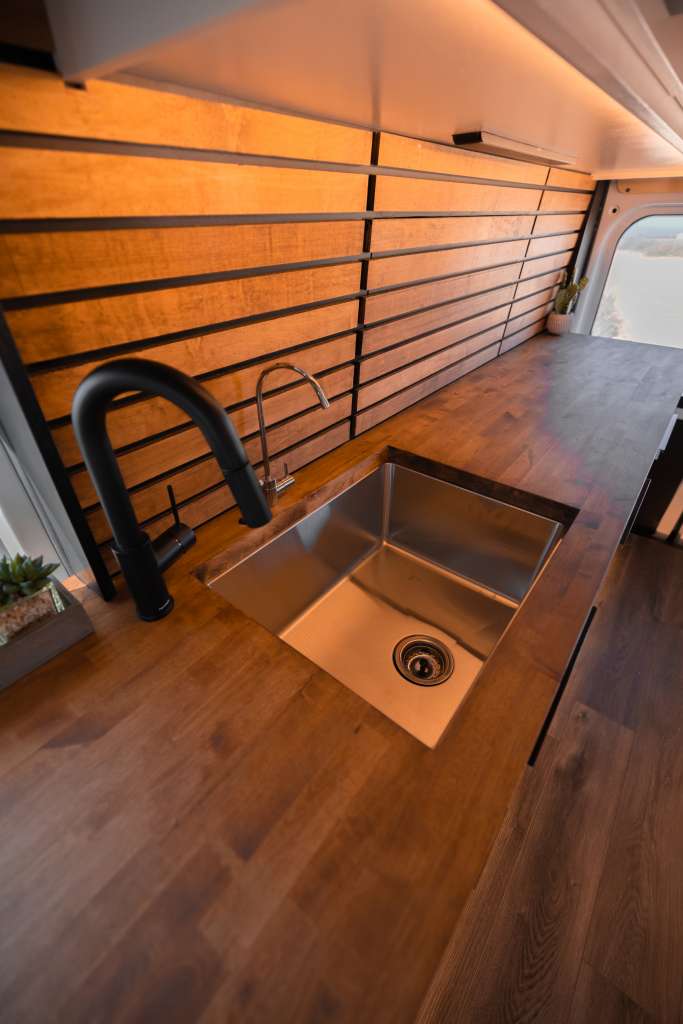 focused on his laptop and phone with coffee nearby. Ideal remote workspace.|Cozy RV rental interior with grey bench seating