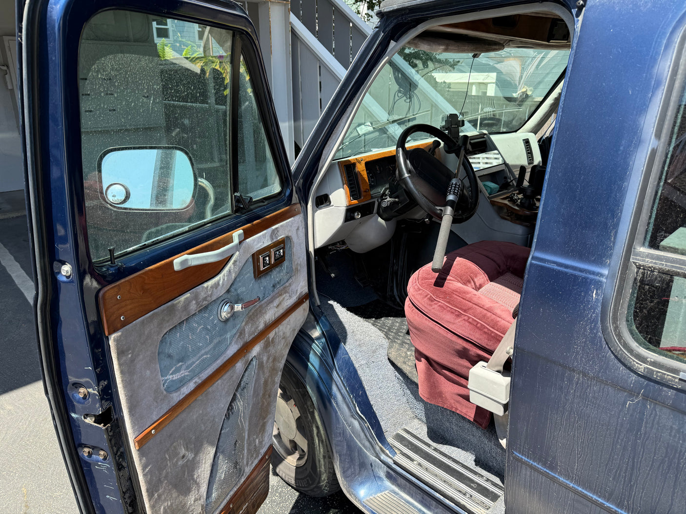 Open driver's door of a blue van, revealing the retro interior with a red seat & steering wheel. A classic rv rental option.