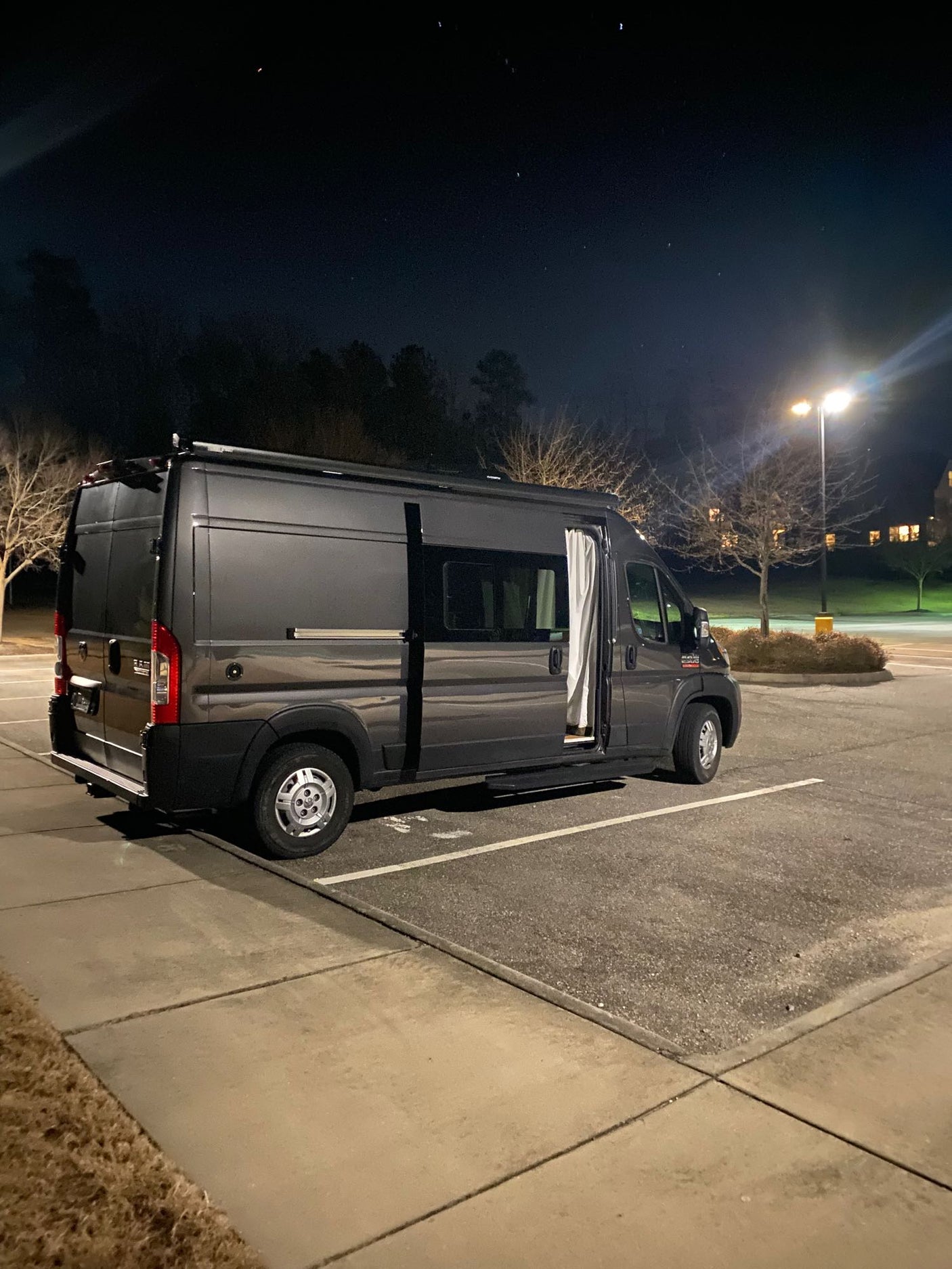 and clever storage solutions.|Cozy RV rental bed with an expansive view of a serene lake