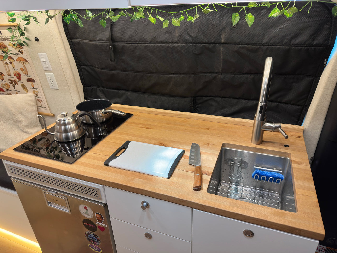 Compact RV rental kitchen with cooktop, sink, fridge, and ample counter space for cooking on the go.