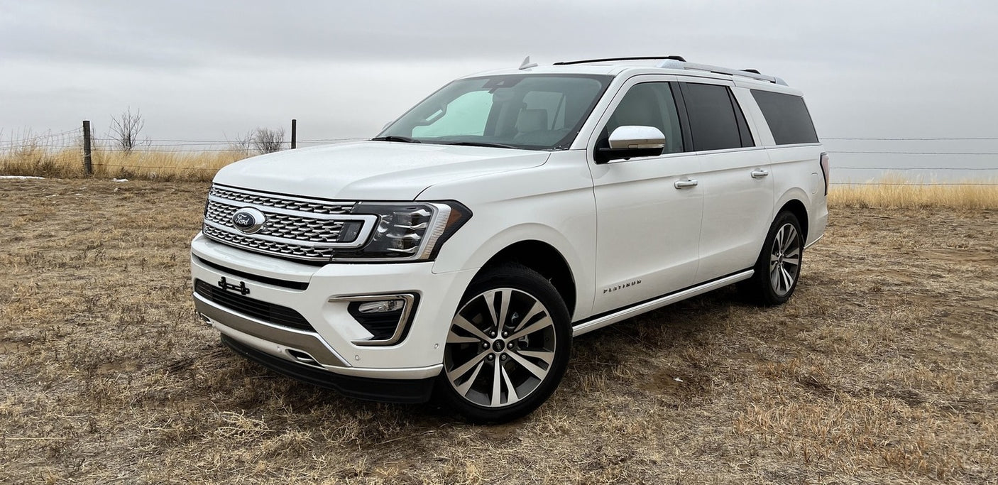 White Ford Expedition SUV, a large and comfortable vehicle in a field. Explore spacious travel options like an rv rental.