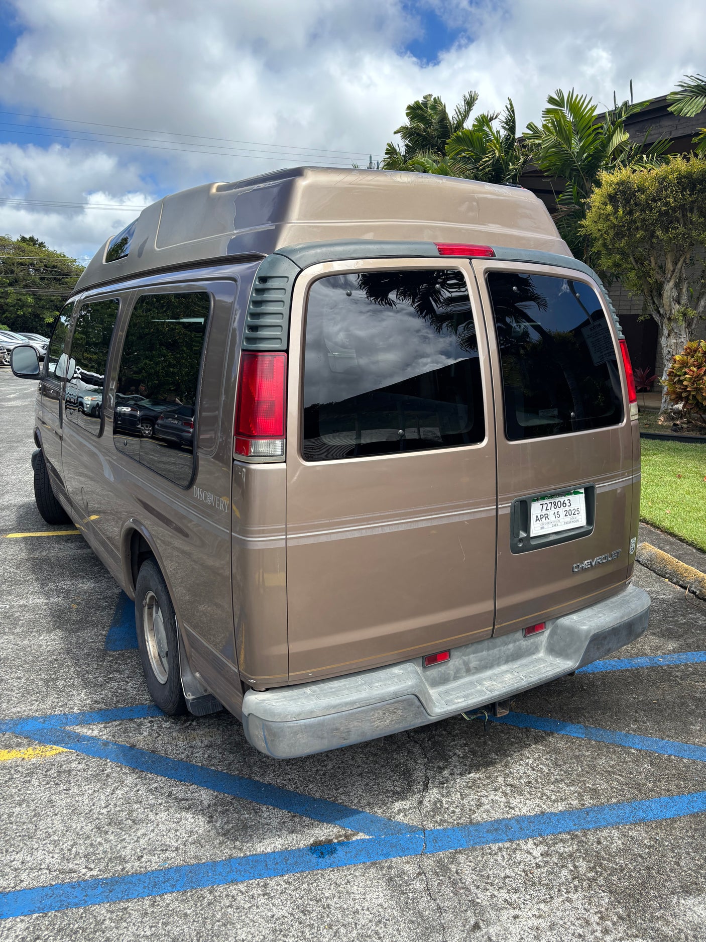 Tan Chevrolet Discovery camper van, likely an RV rental, parked with its distinctive high roof.