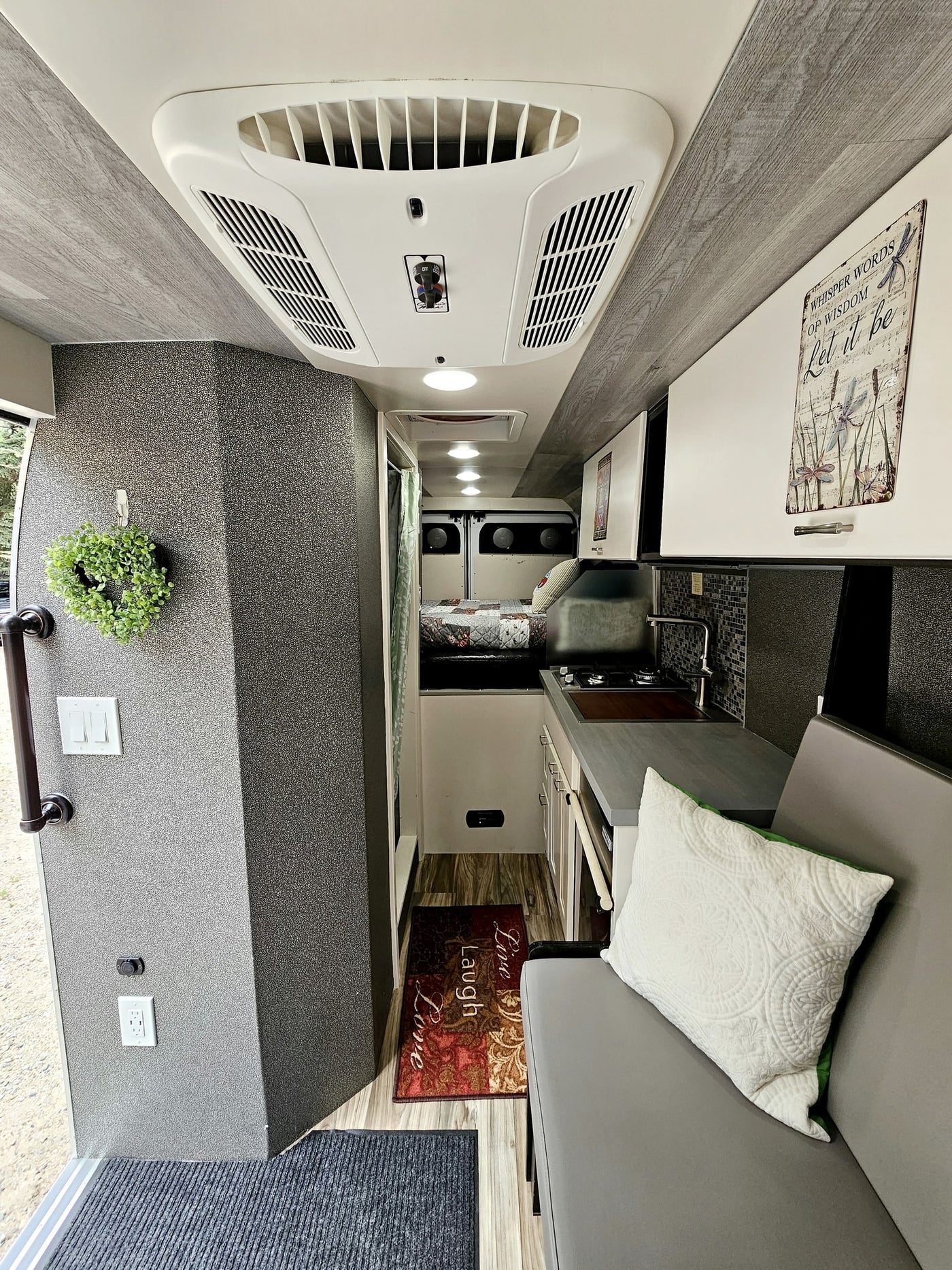 is parked on gravel amidst green trees.|White Ram ProMaster camper van RV rental parked on a gravel road amidst green trees — photo 14