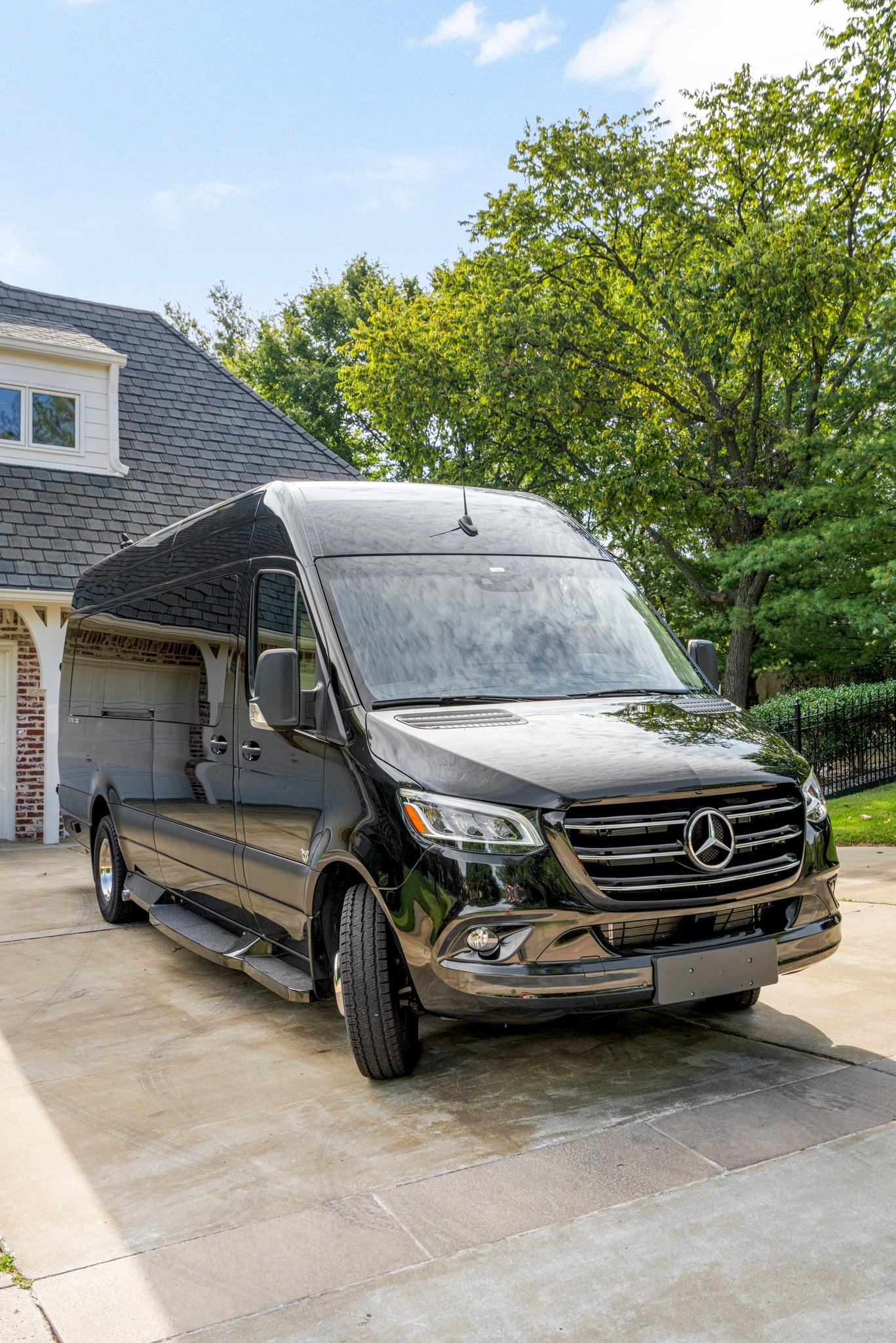 Black Mercedes-Benz Sprinter van, a luxury RV rental option, parked in a residential driveway.