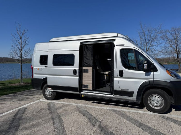 great for your next RV rental road trip.|A silver Winnebago Solis RV rental is parked by a serene lake