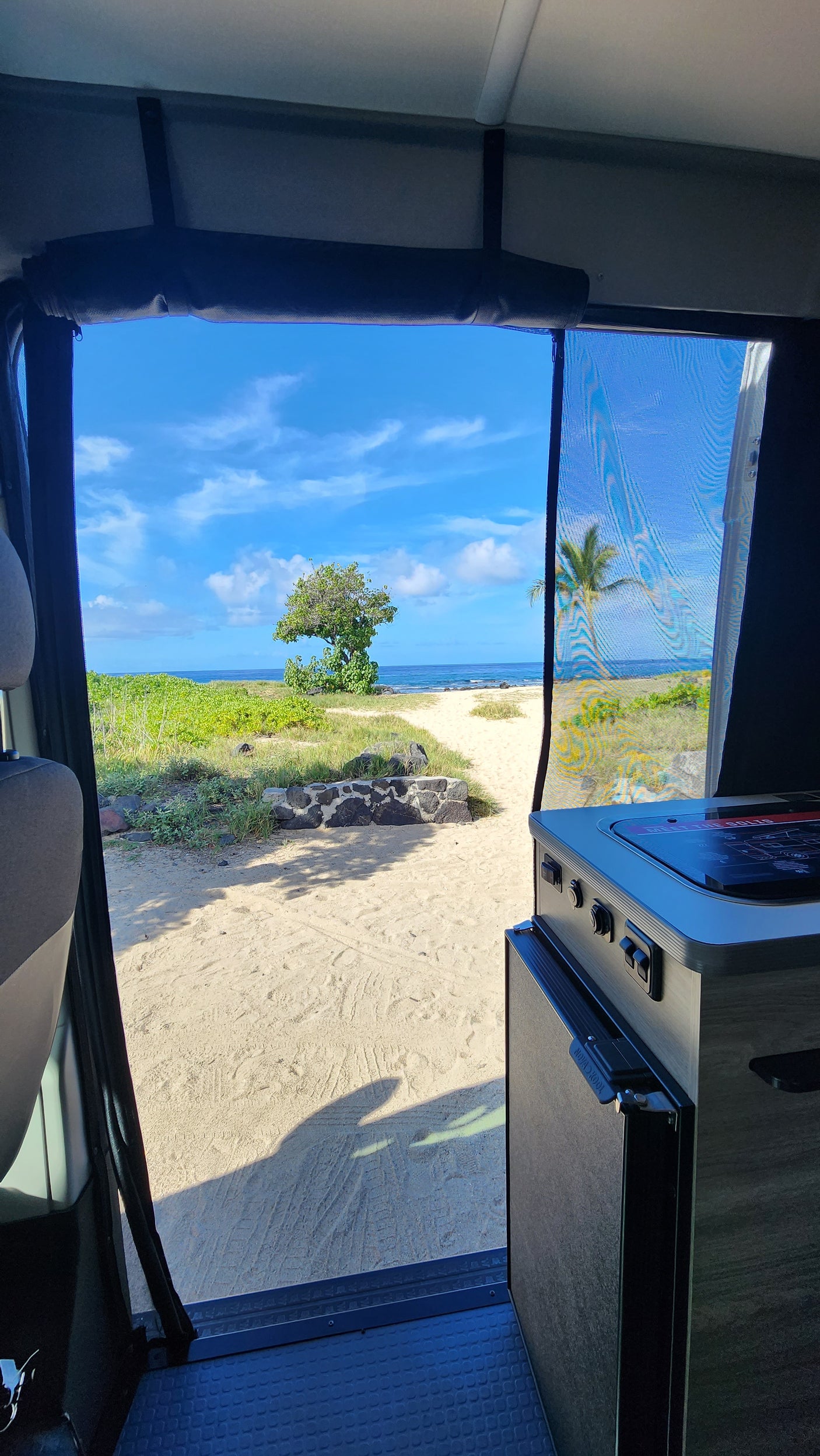 Inside a comfortable rv rental, gaze at the serene beach. View through the large window shows sand, ocean, and sky.
